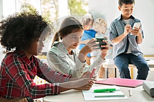 Diverse multiethnic kids school students using smartphones in classroom.