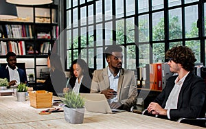 Diverse and multiracial smart businesspeople wearing formal suits, using computer, working, meeting, brainstorming together about