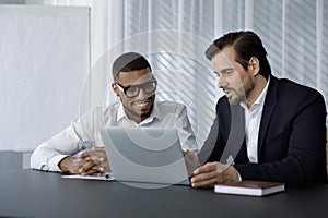 Diverse office employees in formalwear of using laptop computer together