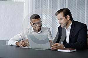 Diverse office employees in formalwear of using laptop computer together photo
