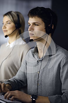 Diverse people group in call center. Businessman talking by headset while sitting in modern office