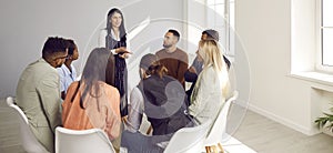Diverse people sitting in circle take part in group therapy session at psychotherapy meeting.