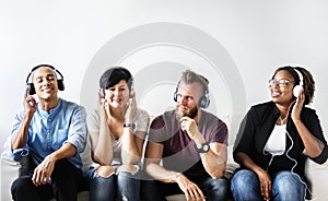 Diverse people sitting on the couch wearing headphones