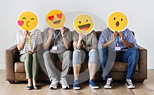 Diverse people sitting and covering face with emojis boards