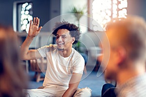 Diverse people in startup business meeting raising hand