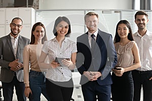 Diverse professional business leaders posing with multicultural workers in office