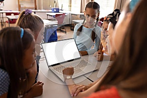 Diverse schoolchildren with female teacher having laptop video call with copy space in classroom