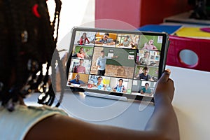 Diverse schoolchildren with male teacher having tablet video call