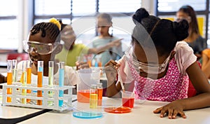 Diverse schoolgirls with chemistry items and liquids in elementary school class