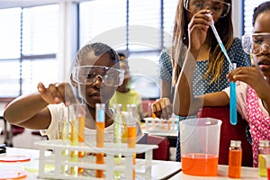 Diverse schoolgirls with chemistry items and liquids in elementary school class