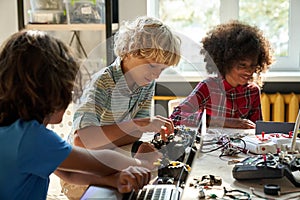 Diverse schoolkids building robotic technologies at STEM educational class.