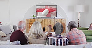 Diverse senior friends watching tv with rugby ball on flag of england on screen