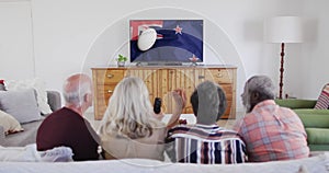 Diverse senior friends watching tv with rugby ball on flag of new zealand on screen