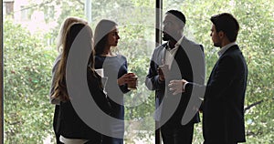 Diverse serious colleagues group talking standing in company hallway