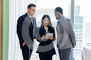 Diverse smart businesspeople standing near window with skyscraper. Ornamented..