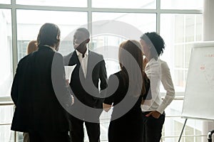 Diverse smiling business people having conversation standing tog