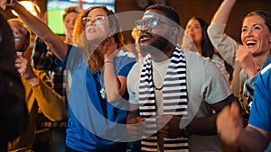 Diverse Soccer Fans Watching a Live Football Match Broadcast in a Sports Pub on TV. People Cheering