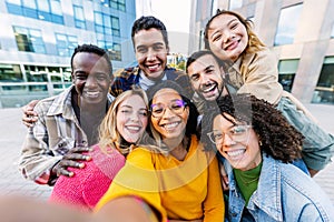 Diverse student group enjoying time together taking selfie with phone outdoors