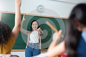 Diverse Student raising their hands up in classroom at international elementary school