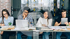 Diverse students studying in university library with gadgets