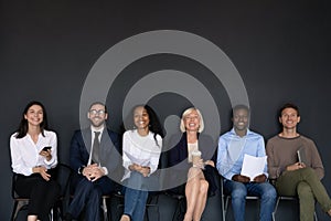 Diverse successful staff seated on chairs smiling looking at camera