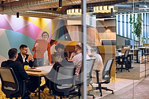 A diverse team of business experts in a modern glass office, attentively listening to a colleague's presentation