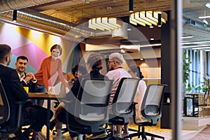 A diverse team of business experts in a modern glass office, attentively listening to a colleague's presentation