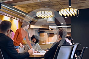 A diverse team of business experts in a modern glass office, attentively listening to a colleague's presentation