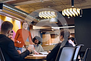 A diverse team of business experts in a modern glass office, attentively listening to a colleague's presentation