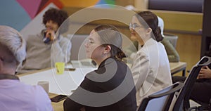 A diverse team of business experts in a modern glass office, attentively listening to a colleague's presentation