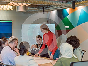 A diverse team of business experts in a modern glass office, attentively listening to a colleague's presentation