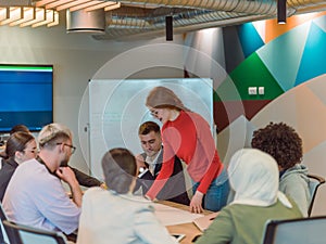 A diverse team of business experts in a modern glass office, attentively listening to a colleague's presentation