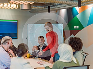 A diverse team of business experts in a modern glass office, attentively listening to a colleague's presentation