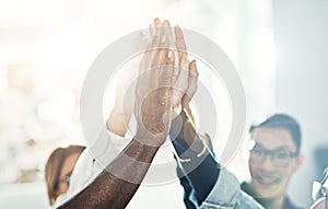 Diverse team of businesspeople high fiving together in an office