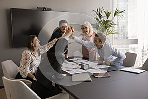 Diverse team of cheerful business colleagues giving group high five