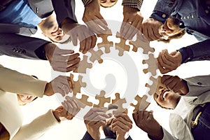 Diverse team of happy business people make a circle from parts of a jigsaw puzzle