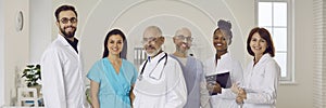 Diverse team of happy doctors who work at one clinic standing together and smiling at camera