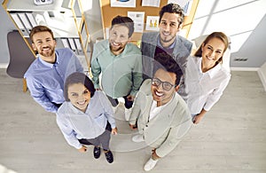Diverse team of happy, smiling business people standing in the office and looking up
