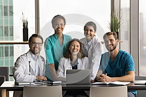 Diverse team of happy young doctors sitting at laptop