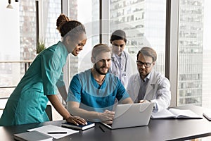 Diverse team of positive successful medical professionals using laptop