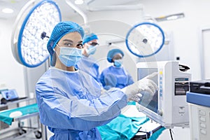 Diverse Team of Professional Surgeons Performing Invasive Surgery on a Patient in the Hospital Operating Room. Nurse Hands Out