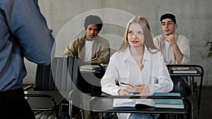 Diverse team young people sitting in classroom attentively listening lecture group leader explaining work strategy