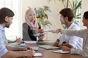 Diverse teammates submitting reports to smiling company boss at office.