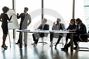 Diverse trainers make whiteboard presentation at team office meeting