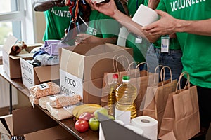 Diverse volunteers collecting food and clothes donations in warehouse photo