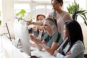 Diverse women coworkers look at computer discuss new common project photo