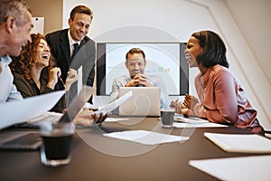 Diverse work colleagues laughing together during a boardroom mee