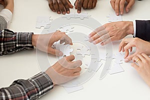 Diverse work team assembling jigsaw at teambuilding activity