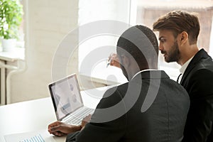 Diverse workers analyzing financial reports at laptop in office