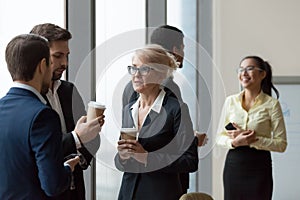 Diverse workers having conversation standing in office at work break